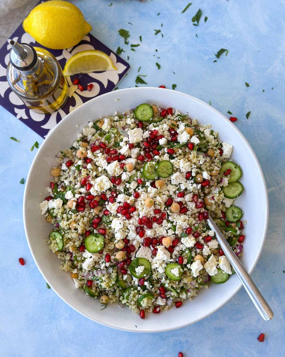 Bright and colorful bulgur salad with chickpeas, cucumber, and pomegranate, ready to serve in a large white bowl.