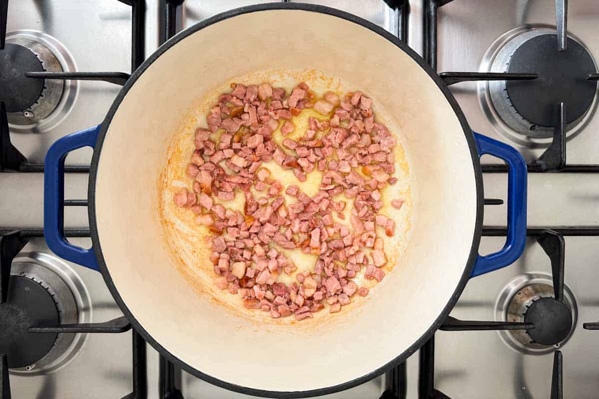 Diced bacon sautéing in a Dutch oven at the start of making Italian Bean Soup.