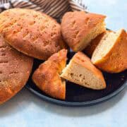 Homemade khobz kesra bread cut into wedges on a plate, showing the soft fluffy inside with a crisp golden crust.