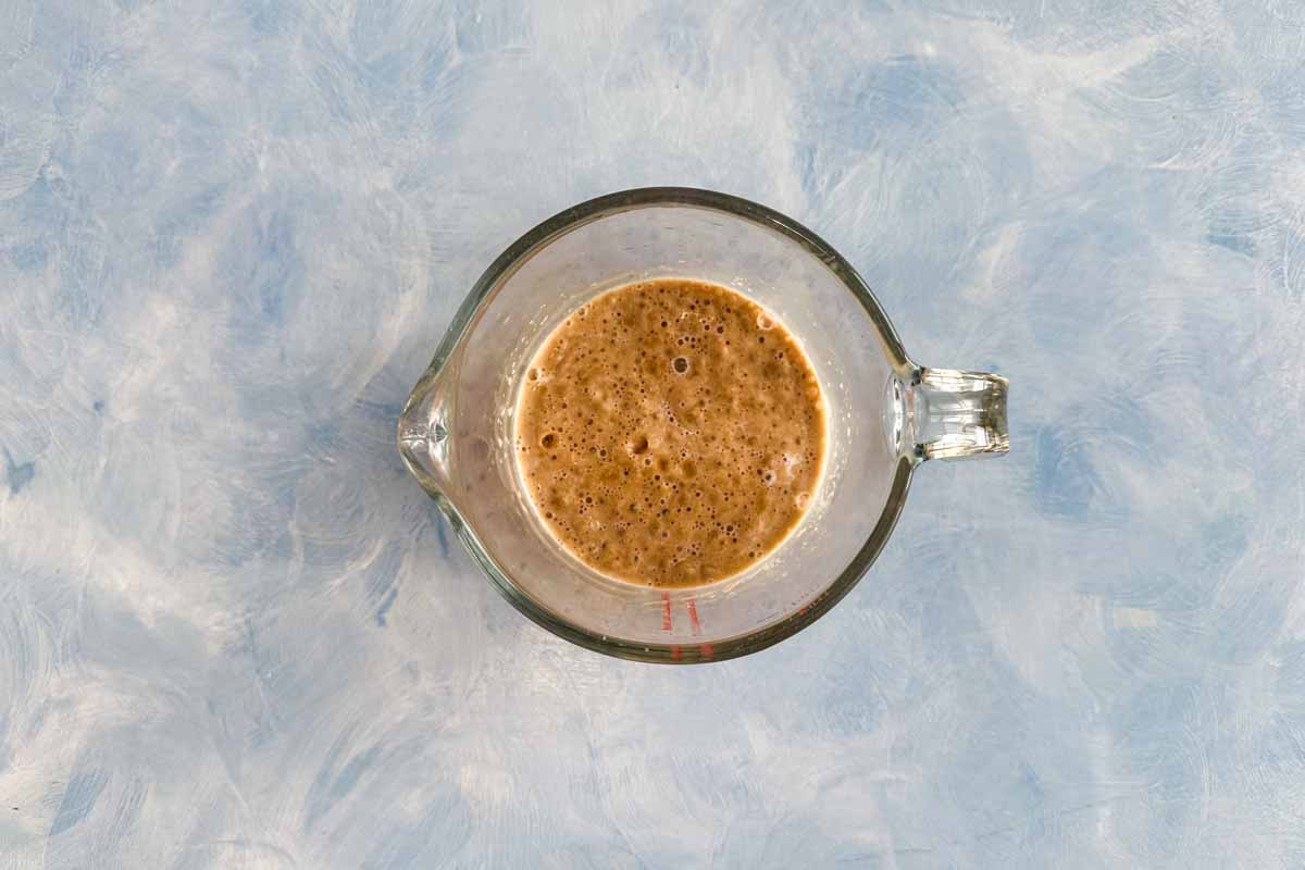 Active yeast mixture bubbling in a glass measuring cup, the first step in making Moroccan bread khobz kesra.