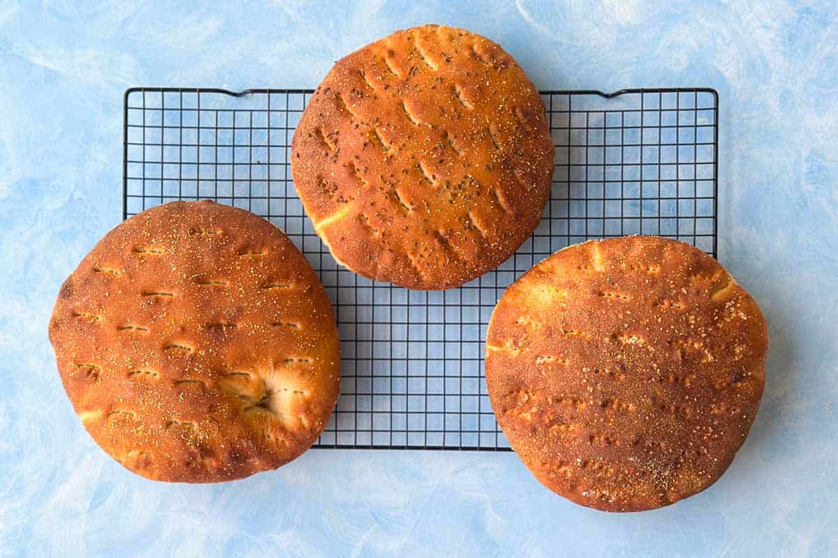 Golden brown Moroccan khobz kesra cooling on a wire rack after baking.