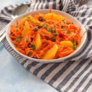 Refreshing carrot mint salad with oranges and raisins, a Moroccan-inspired side dish served in a white bowl.