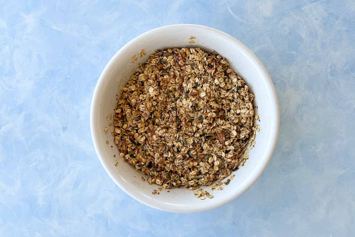 Granola mixture fully coated with the honey and butter mixture, showing a sticky, well-combined texture before baking.