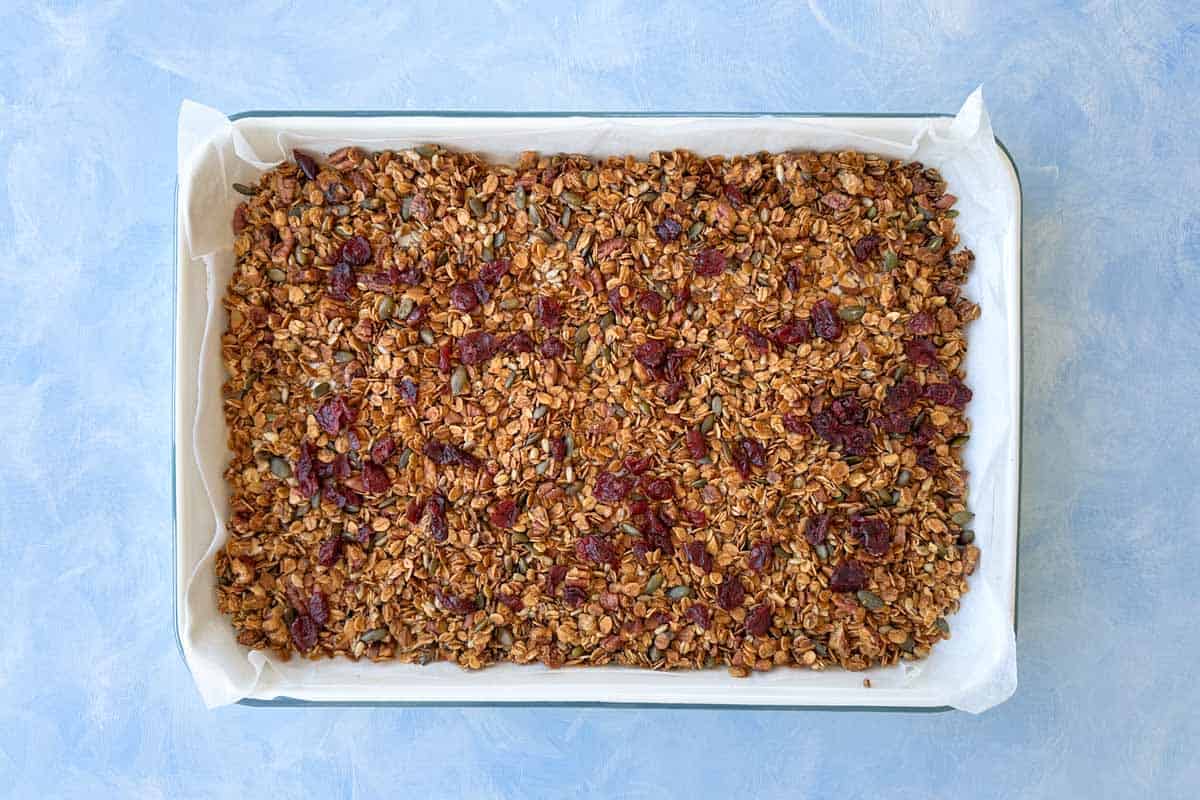 Baked granola topped with dried fruit on a tray, ready to cool before storing or serving.