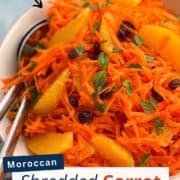 Bright Moroccan shredded carrot salad with orange segments, raisins, and fresh mint in a white bowl. A refreshing vegan side dish with warm spices and citrus dressing.