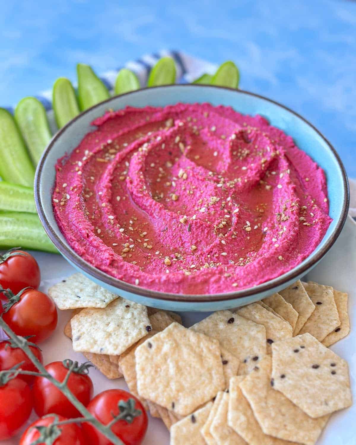 Angled close-up of roasted beet hummus highlighting the creamy texture and rich pink color, garnished with olive oil and seasoning.