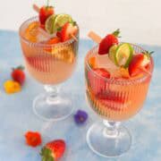 Fresh strawberry and lime rosé sangria in stemmed glasses, garnished with cocktail picks and layered citrus slices.