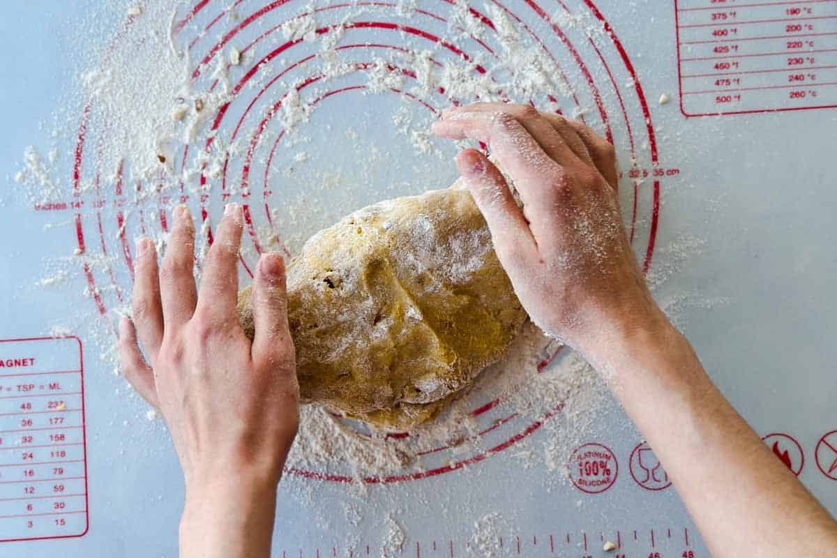 Biscotti dough being shaped and brought together on a floured mat, ready to form into logs for baking.