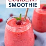 Bright pink cranberry smoothie served in a clear glass with a metal straw, garnished with a fresh cranberry and mint leaf. Vegan cranberry smoothie made with fresh or frozen cranberries, clementines, banana, and pineapple.