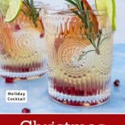 Christmas White Sangria in two vintage-style glasses with lime slices, rosemary sprigs, blood orange, and pomegranate seeds. A festive holiday sangria cocktail with winter citrus and sparkling color. Styled for Christmas and holiday entertaining.