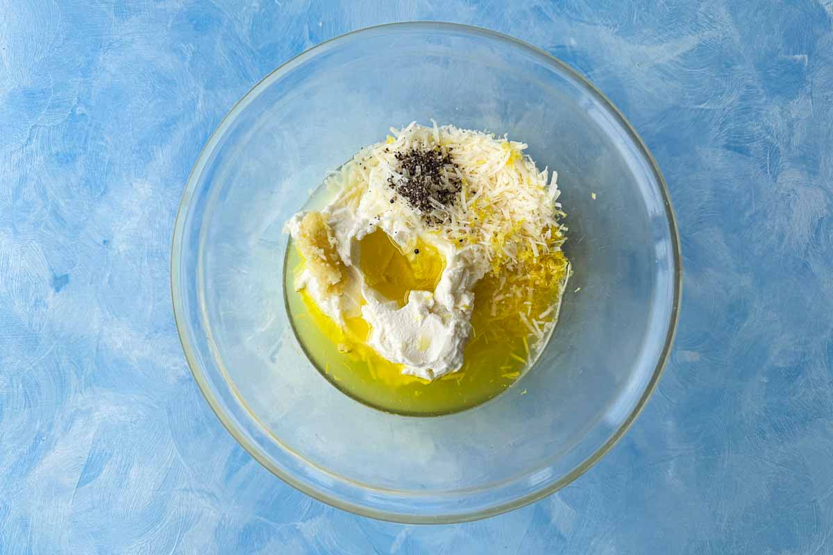 Ricotta, olive oil, parmesan, lemon zest, garlic, salt, and pepper combined in a bowl to create a creamy lemon ricotta sauce.