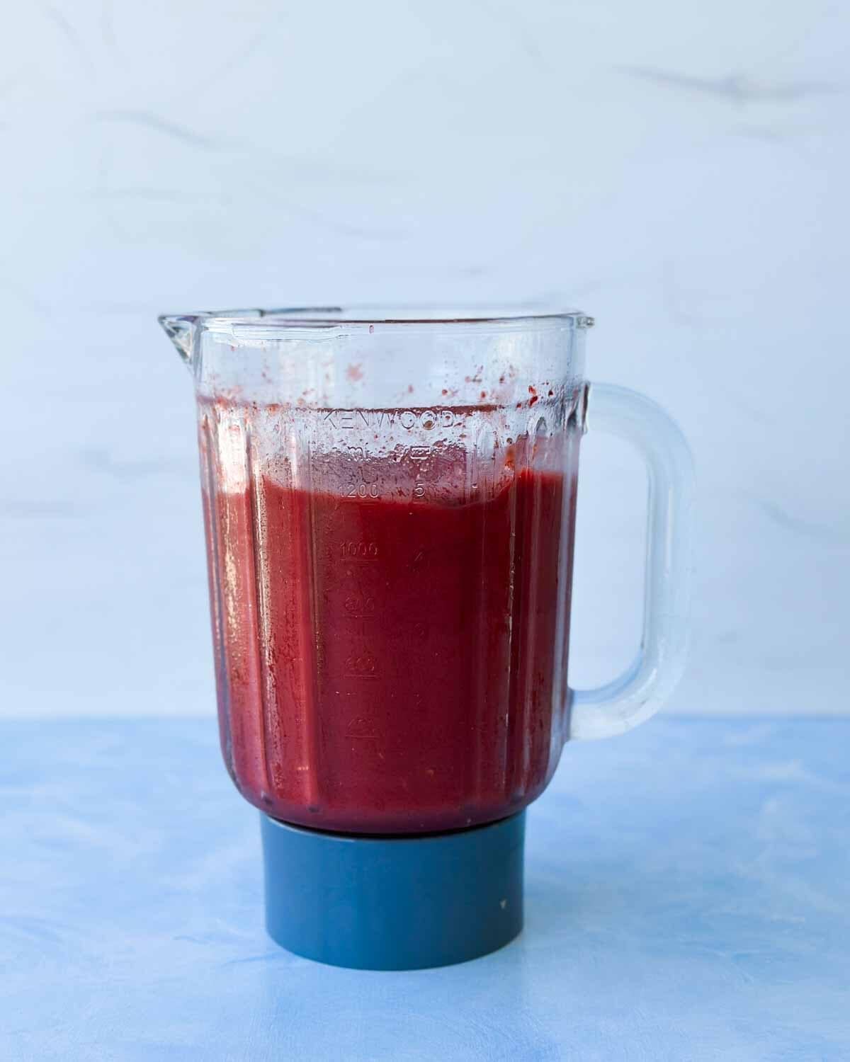 Blended watermelon slushie mixture in a blender pitcher, showing the smooth berry-red texture before serving.