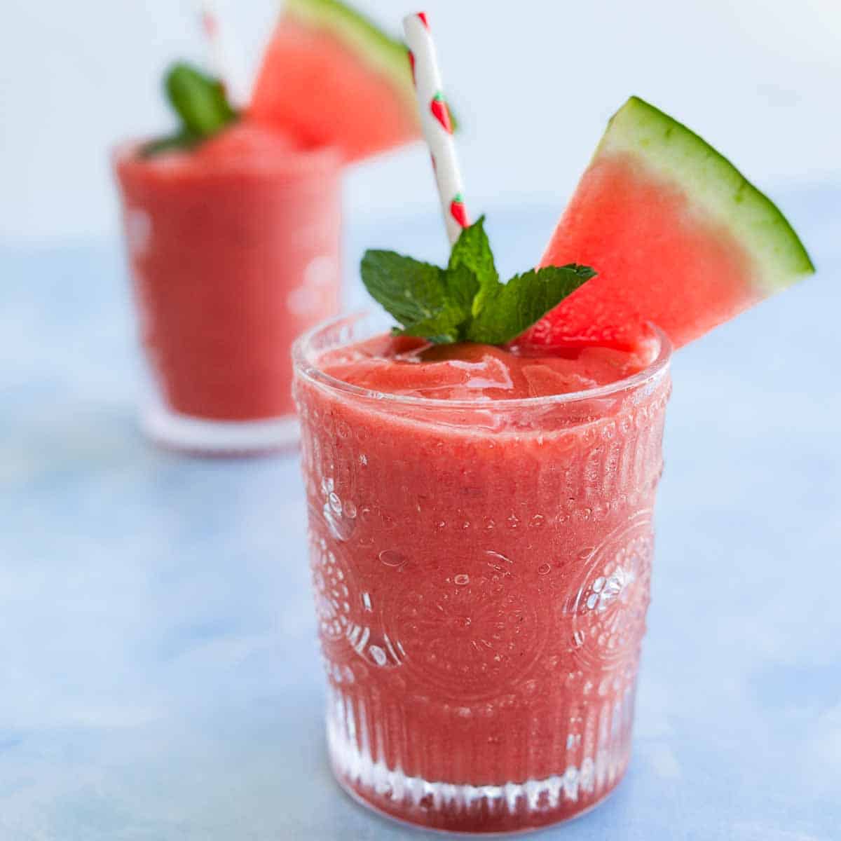 Close-up of a thick watermelon smoothie topped with fresh mint and a juicy watermelon wedge.