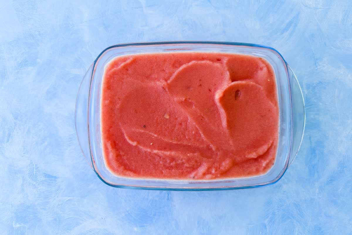 Freshly blended watermelon sorbet mixture spread in a glass container, ready to freeze until firm and scoopable.