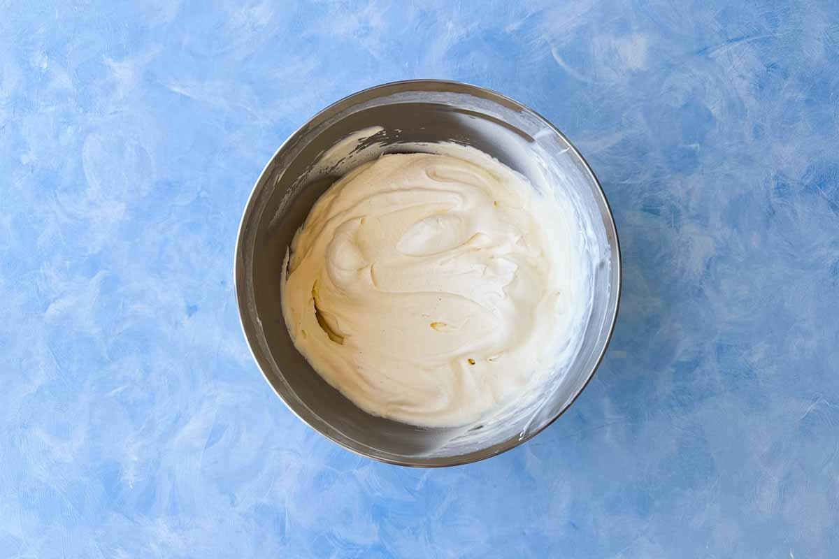 Top view of a mixing bowl filled with freshly whipped mascarpone cream, smooth and thick with soft peaks, ready for layering in the tiramisu.