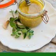 Homemade red wine vinegar dressing in a glass jar with herbs and a spoon.