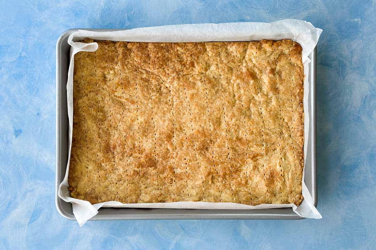 Partially baked shortbread crust for berry crumble bars with a light golden color around the edges.