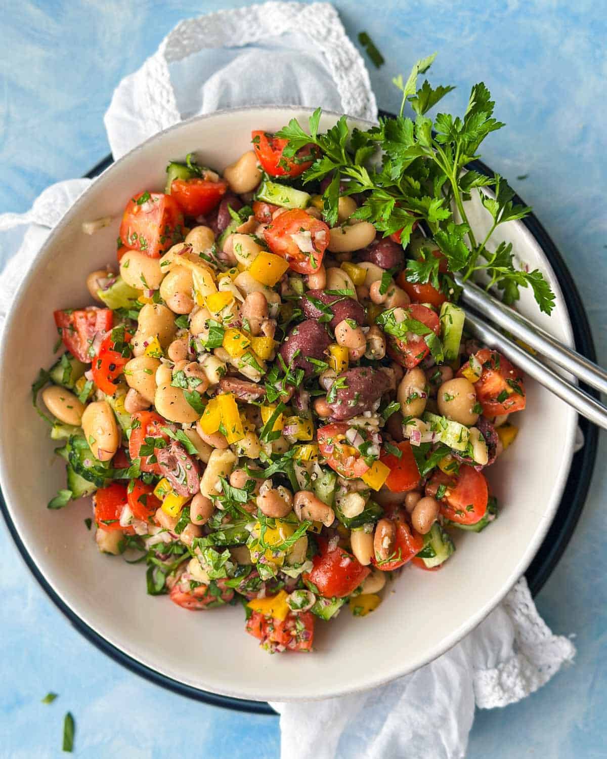 Overhead view of Italian dense bean salad garnished with parsley and served in a white bowl.