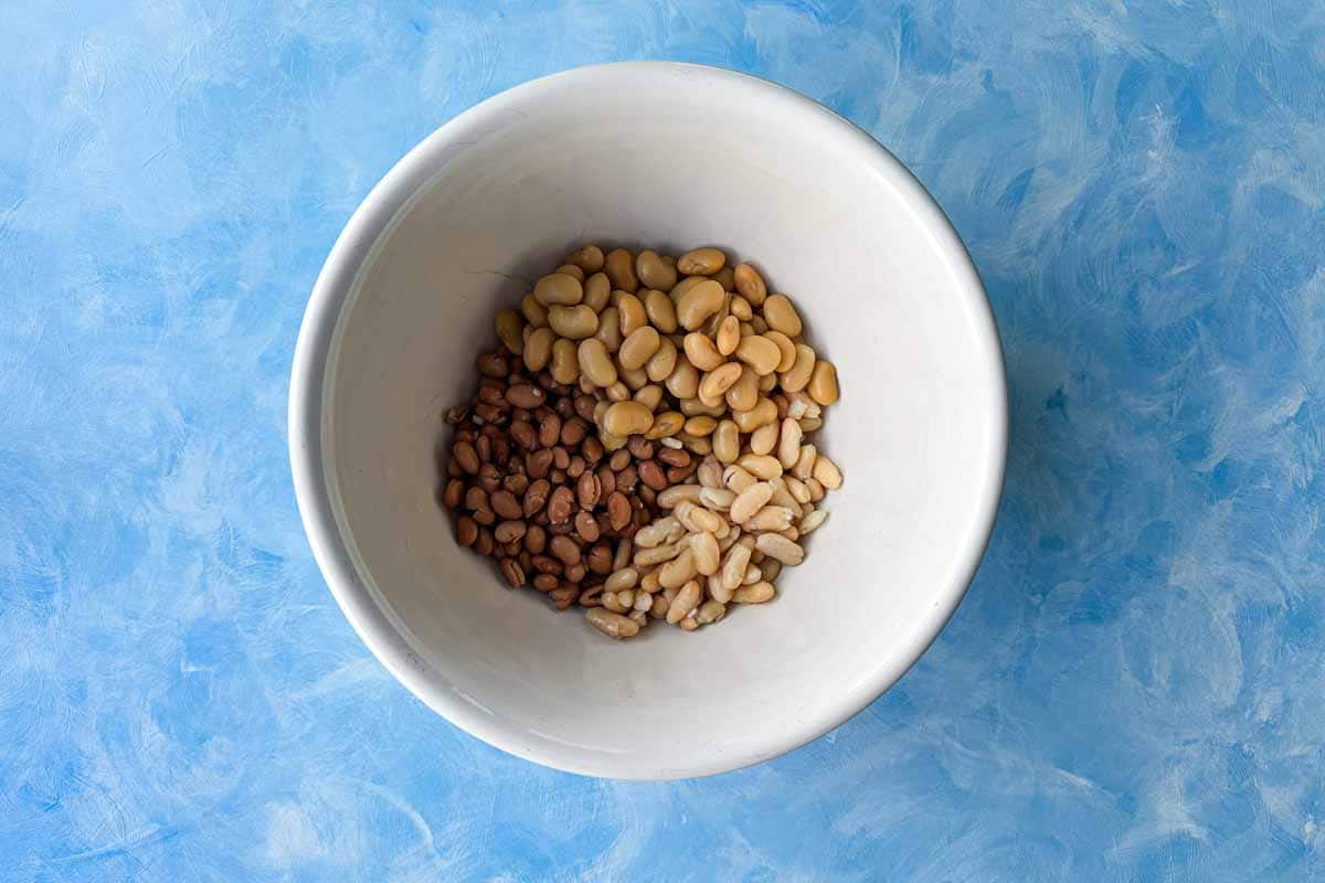 Cannellini beans, butter beans, and borlotti beans added to a large mixing bowl for Italian bean salad.