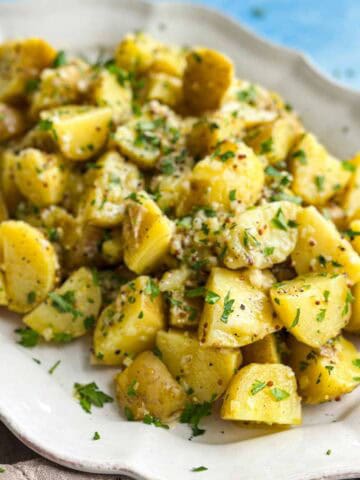 Close-up of French potato salad with warm new potatoes, mustard dressing, fresh parsley, and finely chopped shallots.