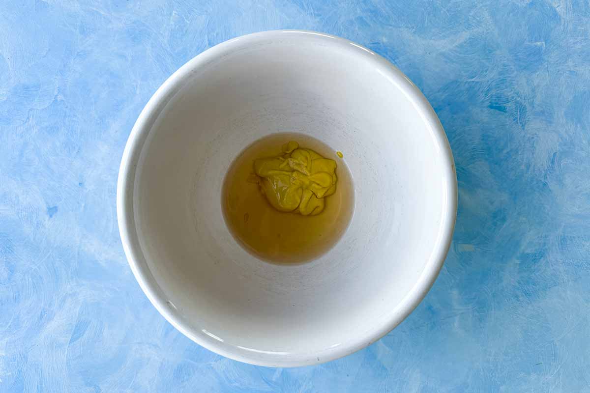 Top view of Dijon mustard and white wine vinegar in a mixing bowl for making classic French vinaigrette.