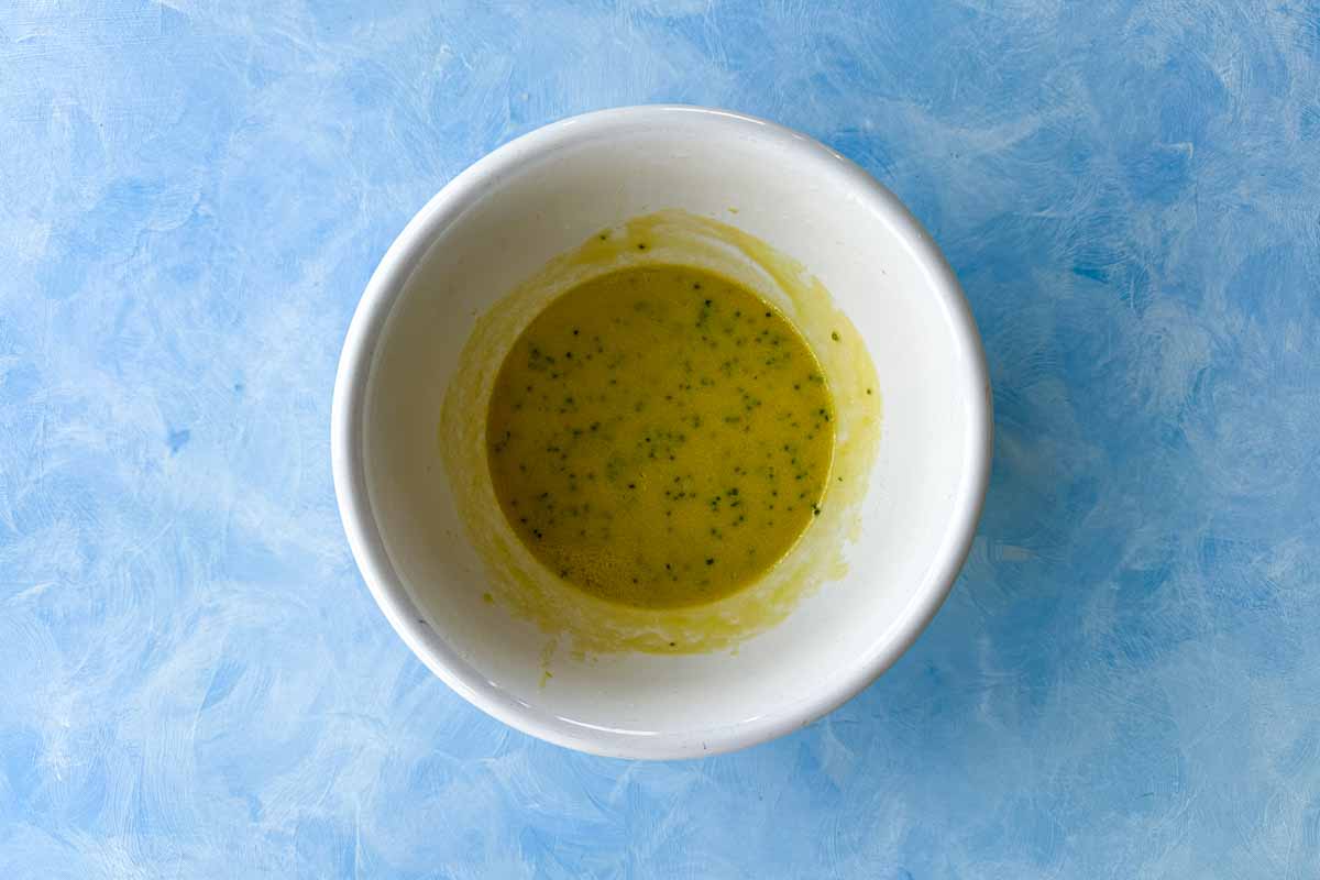 Top view of finished classic French vinaigrette with fresh chives and shallot mixed into the dressing.