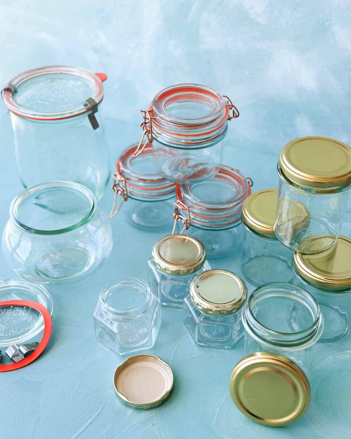 Close-up of clean glass jars and lids in different shapes and sizes for learning how to sterilize jars safely.