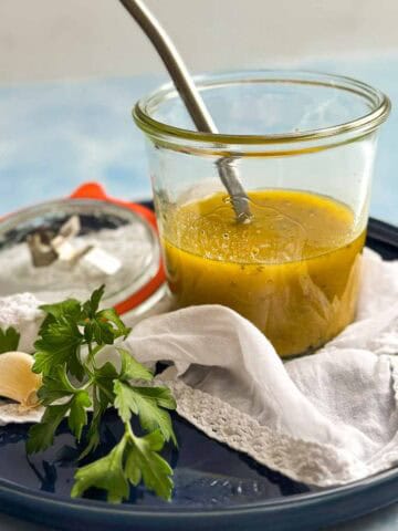 Close-up view of Italian vinaigrette with a spoon in a glass jar, showing its smooth, emulsified texture.