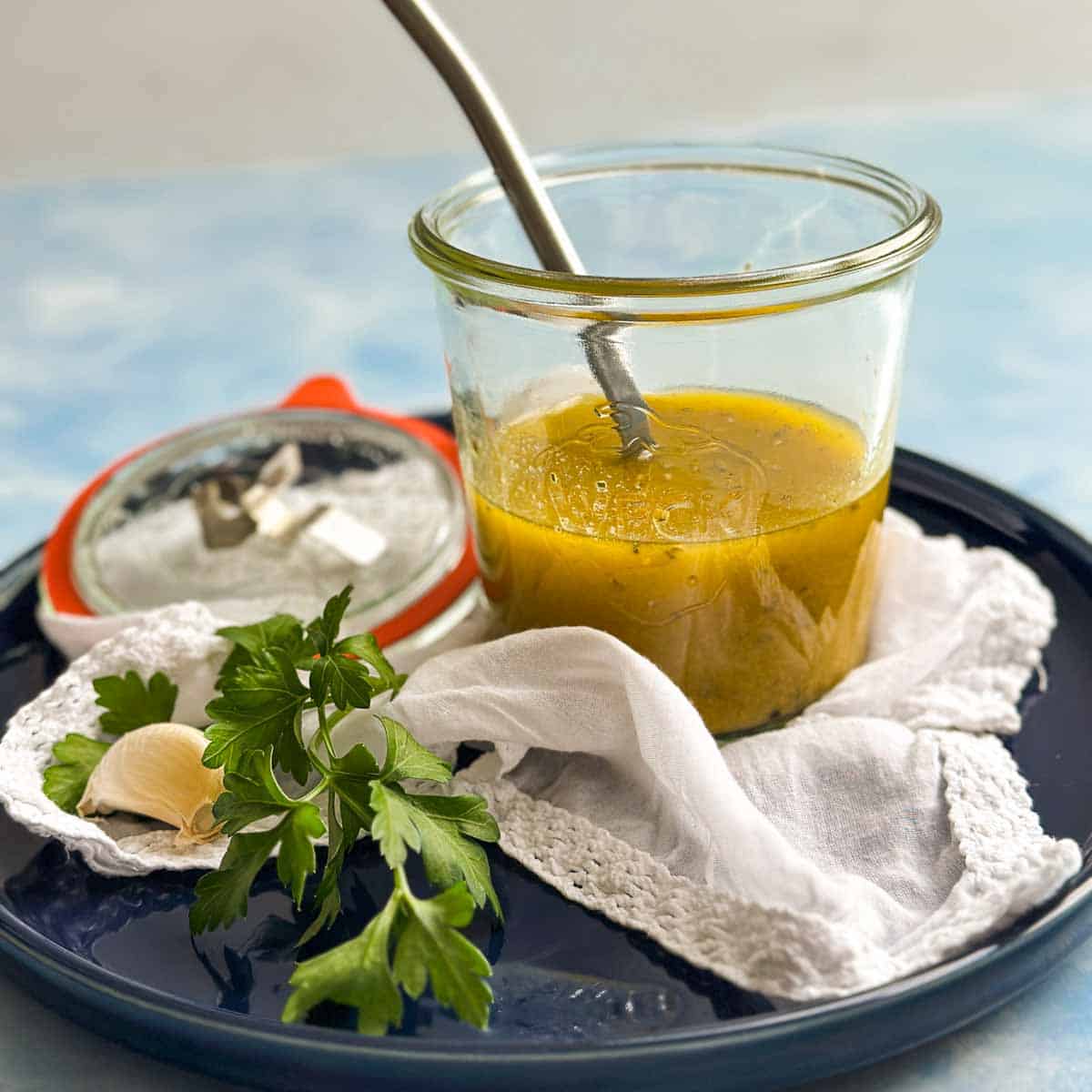 Close-up view of Italian vinaigrette with a spoon in a glass jar, showing its smooth, emulsified texture.