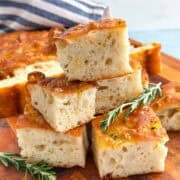 Close-up of thick focaccia bread pieces with golden olive oil crust, airy texture, and rosemary garnish.