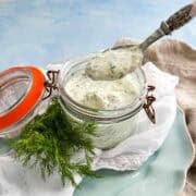 Close-up of a spoonful of creamy herb dressing showing its thick texture and fresh herb flecks.