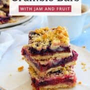 Close-up of berry jam crumble bars with golden topping on a white plate.