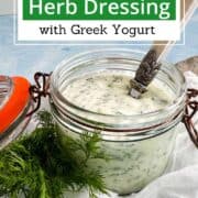 Herb dressing in glass jar with fresh herbs and Greek yogurt.