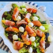 Fresh peach, mozzarella, and prosciutto salad on a white platter.