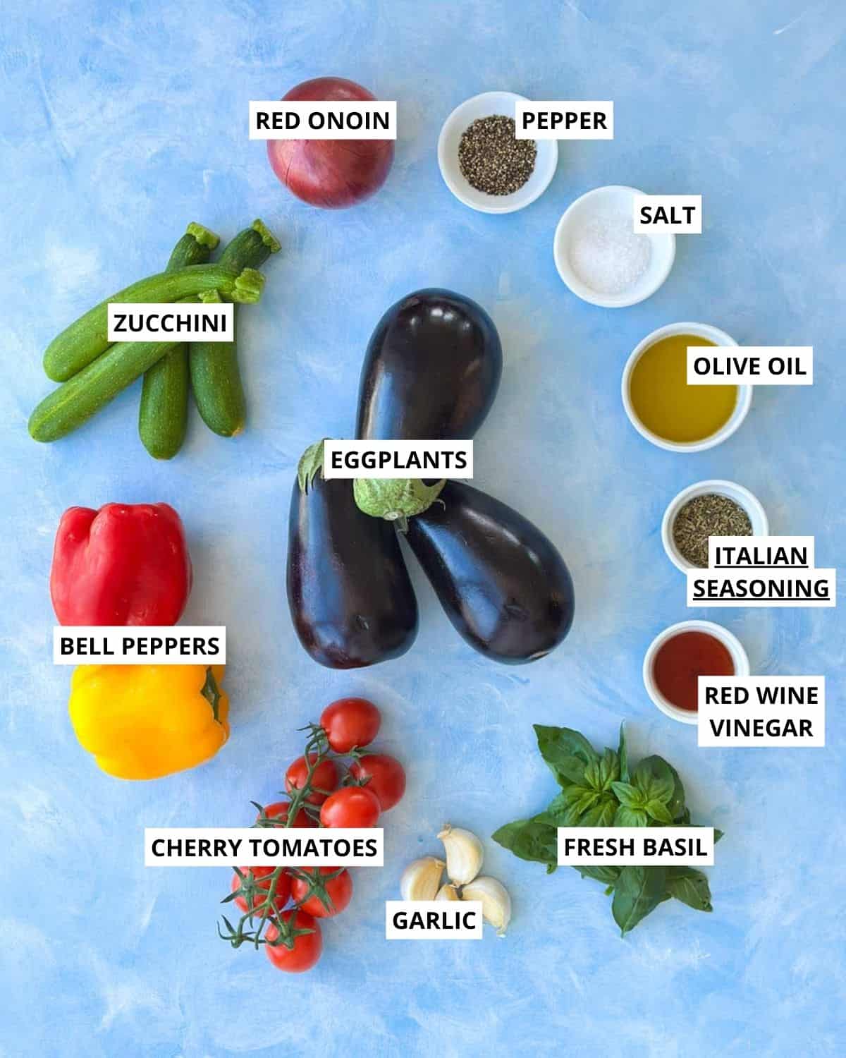 Overhead ingredient shot for Mediterranean roasted vegetables with eggplant, zucchini, bell peppers, cherry tomatoes, red onion, basil, garlic, and Italian seasonings.