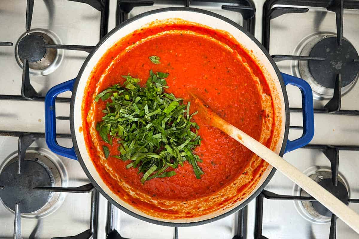 Fresh basil added to a pot of spicy tomato pasta sauce after simmering.