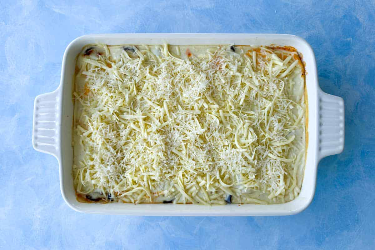 Top view of fully assembled Mediterranean vegetable lasagna topped with mozzarella and Parmesan before baking.