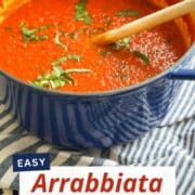 A pot of spicy Arrabbiata sauce with fresh herbs and chili peppers.