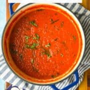 Close-up of spicy Arrabbiata pasta sauce in a pot with herbs.