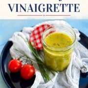 Classic French Dijon vinaigrette in a glass jar with tomatoes and herbs.
