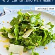 Fresh rocket salad with lemon and Parmesan cheese on a white plate.