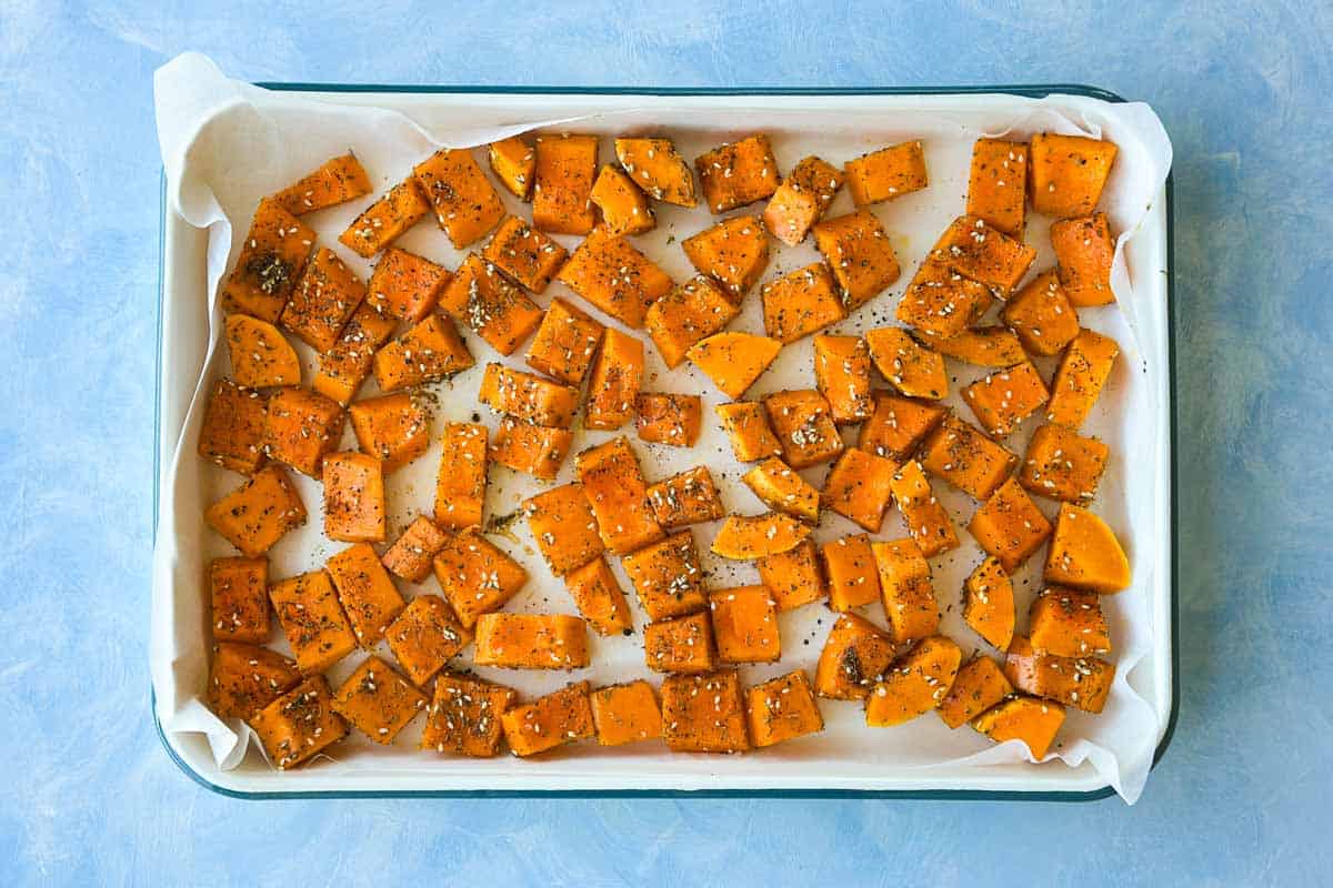 Butternut squash pieces seasoned with za'atar on a parchment-lined baking tray before roasting.