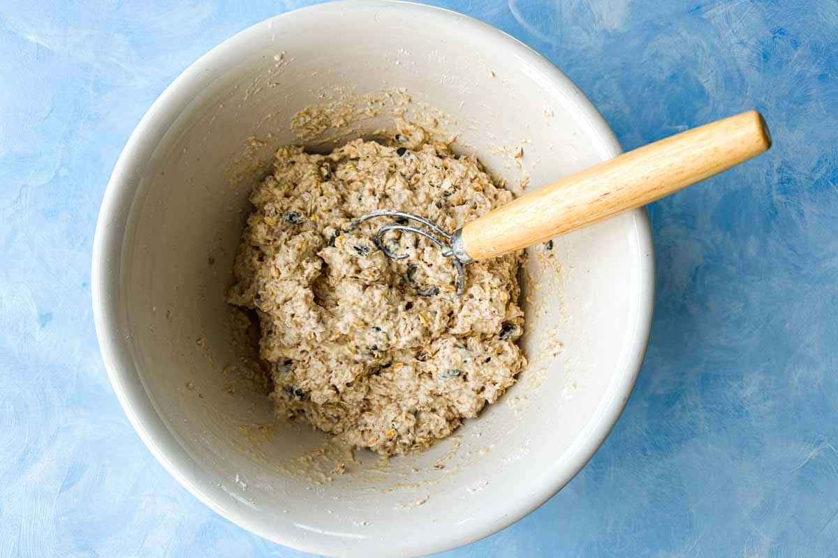 Shaggy no-knead bread dough mixed with a spoon in a bowl.
