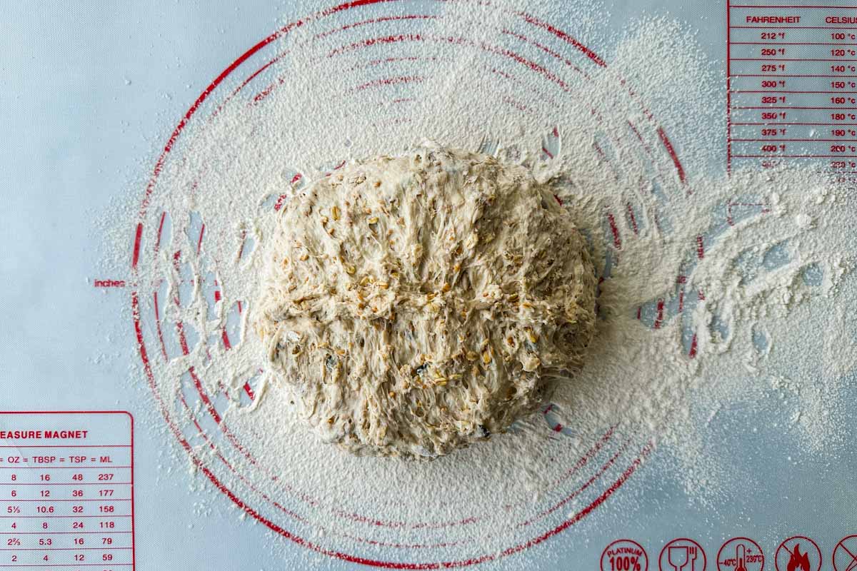 Shaped dough ball resting on a floured baking mat.