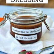 Homemade pomegranate molasses salad dressing in a glass jar with fresh pomegranate seeds.