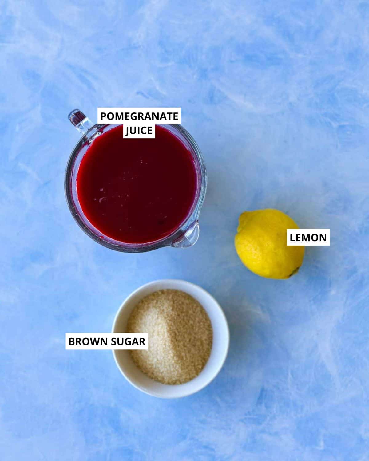 Ingredients for homemade pomegranate molasses, including pomegranate juice, brown sugar, and lemon.