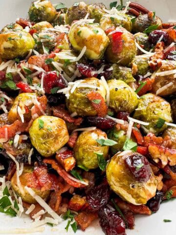 Extreme close-up of balsamic-glazed brussels sprouts with bacon, pecans, and cranberries.