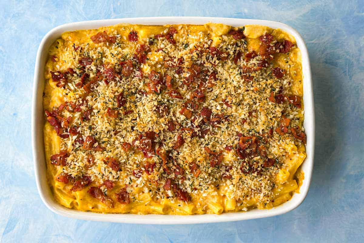 Freshly baked butternut mac and cheese in a white dish, the breadcrumb topping golden and the bacon crisp.