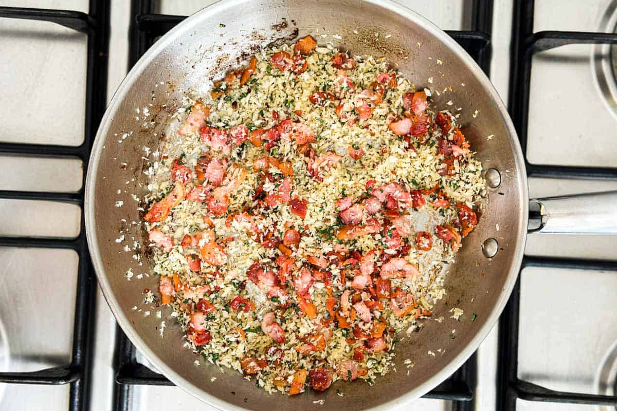 Panko breadcrumbs and chopped herbs toasting with bacon in a skillet to make the crunchy topping.