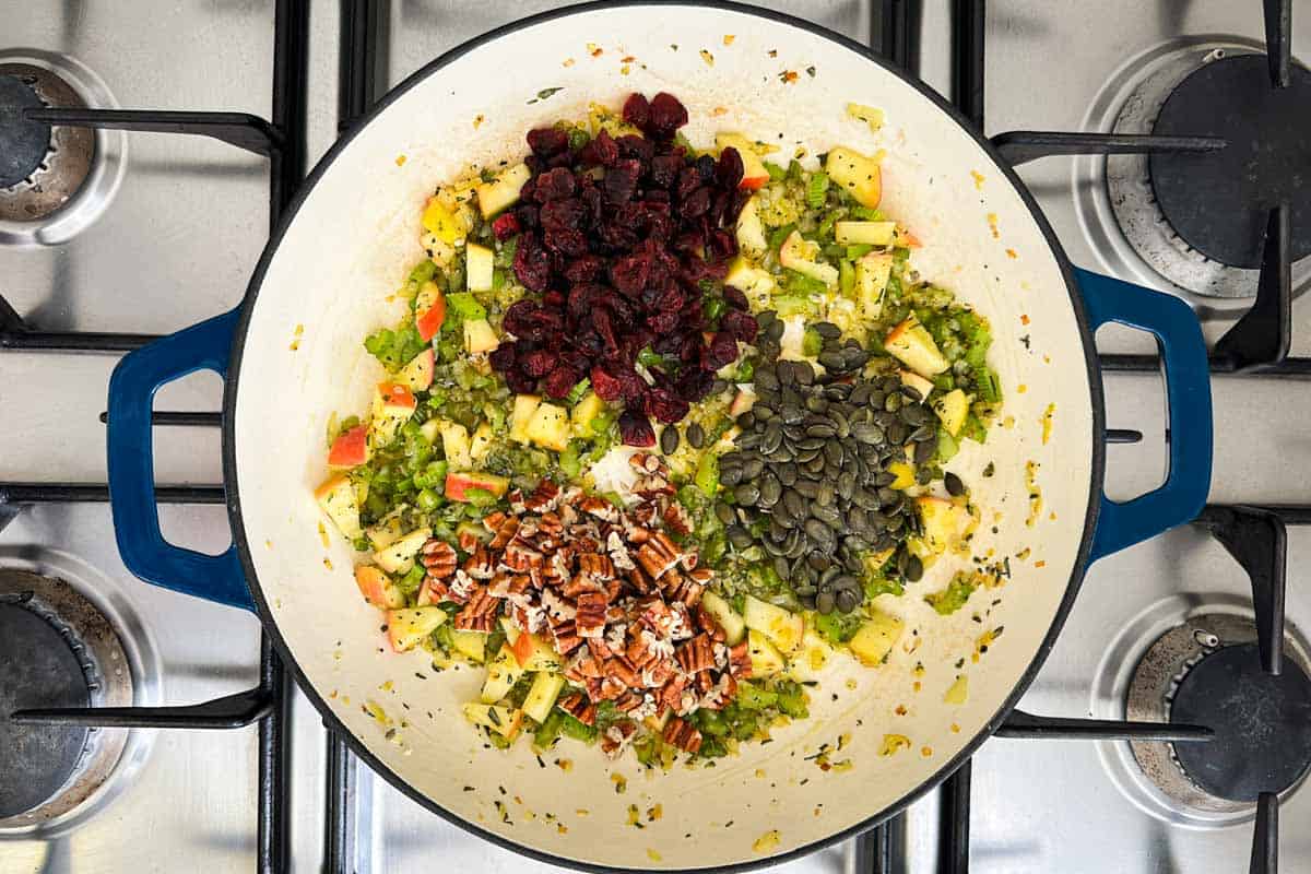 Dried cranberries, pumpkin seeds, and chopped pecans added in separate piles atop the apple and celery mixture.